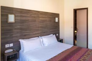 サン・ラファエルにあるホテル ル21 のベッドルーム1室(大型ベッド1台、木製ヘッドボード付)
