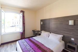 a bedroom with a large bed with a wooden headboard at Hotel Le 21 in Saint-Raphaël