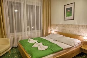 a bedroom with a large bed with a green blanket at Hotel Zerrenpach in Osrblie