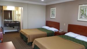 a hotel room with two beds and a sink at Regency Inn in Moreno Valley