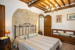 a bedroom with a bed and a stone wall at Casale del Bosco by VacaVilla in Casole dʼElsa