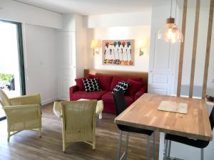 Una sala de estar con un sofá rojo y una mesa. en Appartement cosy à Saint-André-des-Eaux de 47 m² avec jardin, en Saint-André-des-Eaux