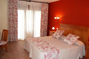 a bedroom with a bed with red walls and a window at Hotel El Cortijo de Daimiel in Daimiel