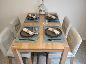 a wooden table with chairs and plates and wine glasses at LES JACINTHES in Berck-sur-Mer +2 photos