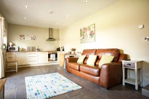 ein Wohnzimmer mit einem braunen Ledersofa und einer Küche in der Unterkunft Hillcroft Accommodation in Redhill
