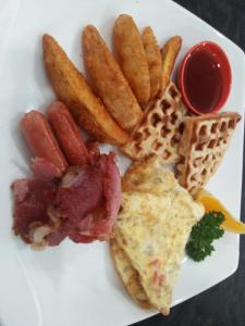 a plate of food with eggs bacon and french fries at Kandyan Reach Hotel in Kurunegala