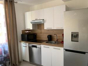 a kitchen with white cabinets and a sink and a refrigerator at Magnifique Studio au cœur historique de Fréjus in Fréjus