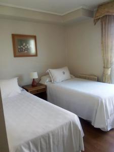 2 camas en una habitación de hotel con sábanas blancas en RoomApart Escuela Militar, en Santiago