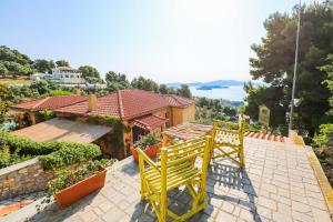 - deux chaises jaunes assises sur une terrasse en face d'une maison dans l'établissement Absolute vacation luxury Villa Stratos near sea majestic view, à Achladies