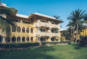 a large yellow building with palm trees in front of it at Iberostar Waves Paraíso del Mar - All Inclusive in Puerto Morelos