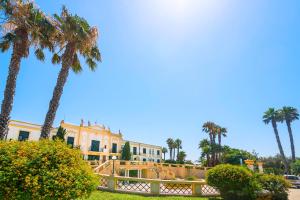 una casa con palme e una recinzione di Delfino Beach Hotel a Marsala