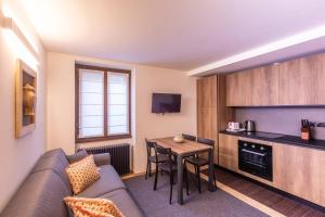 ein Wohnzimmer mit einem Sofa und einem Tisch sowie eine Küche in der Unterkunft ALTIDO Warm Flat for 4, with Parking in Courmayeur in Courmayeur