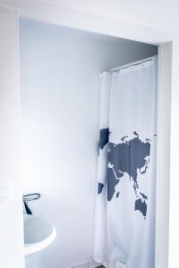 a bathroom with a white shower curtain with a map of the world at B&B 1 uit de 100 in Ghent