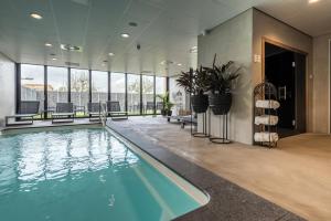 a swimming pool in a hotel lobby with windows at Fruitpark Hotel & Spa in Ochten