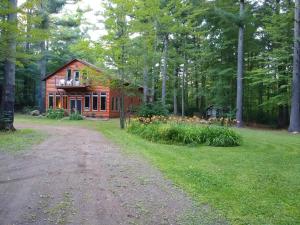 une maison dans les bois avec un chemin de terre devant dans l'établissement Bed and breakfast suite at the Wooded Retreat, à Pine City