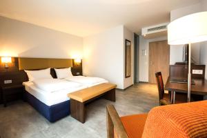 ミュンヘンにあるdomus Hotelのベッド2台とテーブルが備わるホテルルームです。