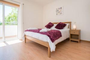 um quarto com uma cama com lençóis roxos e uma janela em Central Modern 2 Bed Apartment Armacao De Pera em Armação de Pêra