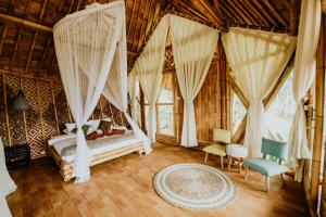 a bedroom with a bed in a room with curtains at Bird Hills Bamboo House in Karangasem