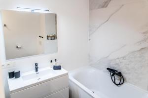 bagno bianco con lavandino e specchio di B&B 1 uit de 100 a Gand