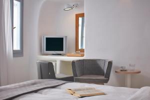 a bedroom with a desk with a computer and a chair at Cliff Side Suites in Firostefani
