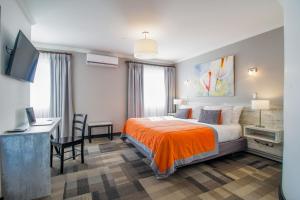 Angolにある202 Hotel Boutiqueのベッド、デスク、テレビが備わるホテルルームです。