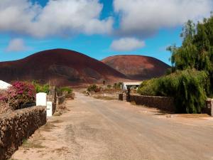 a dirt road with two hills in the distance at Villa Shepherd Lajares - LUXURY VILLA FUERTEVENTURA in Lajares