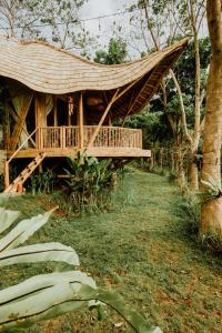 a bamboo house with a porch and a hammock at Bird Hills Bamboo House in Karangasem