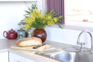 un pain sur une planche de découpe à côté d'un évier dans l'établissement Bundle Hill Cottages, à Bawley Point 47 autres photos