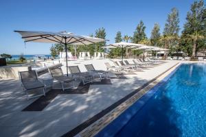 門菲的住宿－杜納度假酒店，水边带椅子和遮阳伞的游泳池