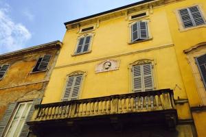 a yellow building with a balcony with a clock on it at Appartamento Petrarca in Parma
