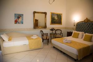 ナポリにあるB＆B アート スイート サンタ ブリージダのベッド2台、テーブル、鏡が備わる客室です。