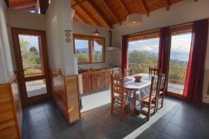 eine Küche mit einem Tisch, Stühlen und Fenstern in der Unterkunft La Patagonia Secreta in Villa Pehuenia