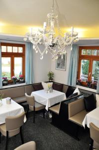 a restaurant with two tables and chairs and a chandelier at Villa Waldperlach by Blattl in Munich