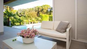 a white couch on a patio with a table and flowers at Villa Riva Beachfront in Lignano Sabbiadoro