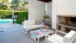 a patio with white furniture and a swimming pool at Villa Riva Beachfront in Lignano Sabbiadoro