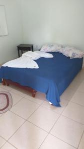 a bed in a room with a blue blanket on it at Chalés AABB Valença RJ in Valença