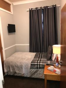 a small bedroom with a bed and a window at The Ocean Inn in Edinburgh