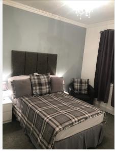 a bedroom with a bed with a plaid blanket and a chair at The Ocean Inn in Edinburgh