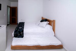 ein Bett mit weißer Bettwäsche und Kissen darauf in der Unterkunft Habitacion Coveñitas 201 in Coveñas
