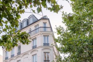 - un bâtiment blanc avec un balcon au-dessus dans l'établissement 9Hotel Bastille-Lyon, à Paris