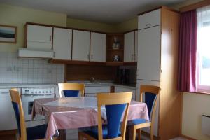 a kitchen with a table and chairs and white cabinets at Maria Aichholzer in Sankt Jakob im Rosental