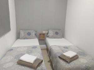 Dos camas en una habitación pequeña con toallas. en Mejor Apartamento en Plaza España con Parking Gratuito, en Barcelona
