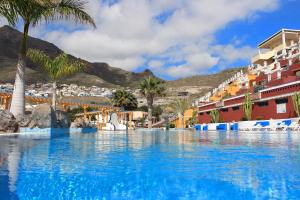 uma grande piscina com palmeiras e edifícios em Costa Adeje VI em Adeje