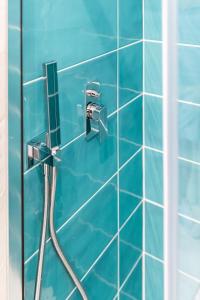 La salle de bains est pourvue d'une douche carrelée de bleu avec un tuyau. dans l'établissement La Smeralda - Boutique Rooms and Breakfast, à Golfo Aranci