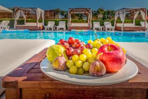 une assiette de fruits sur une table à côté d'une piscine dans l'établissement Chandris Apartments, à Kavos