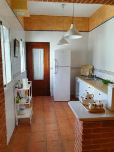 a kitchen with a white refrigerator and a tile floor at Vive la campiña Sevillana - Terraza y 3 Hab in El Viso del Alcor