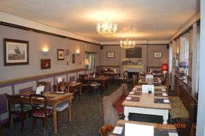 a restaurant with tables and chairs and a chandelier at The Compasses Inn in Fordingbridge