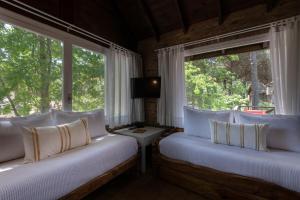 1 dormitorio con 2 camas y 2 ventanas en Carilo Village Apart Hotel & Spa en Cariló