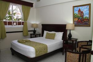 a bedroom with a large bed and two chairs at Platino Hotel & Casino in Santiago de los Caballeros