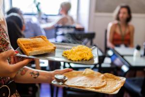 Una mujer sosteniendo una bandeja con alimentos para el desayuno. en Rossio Hostel, en Lisboa